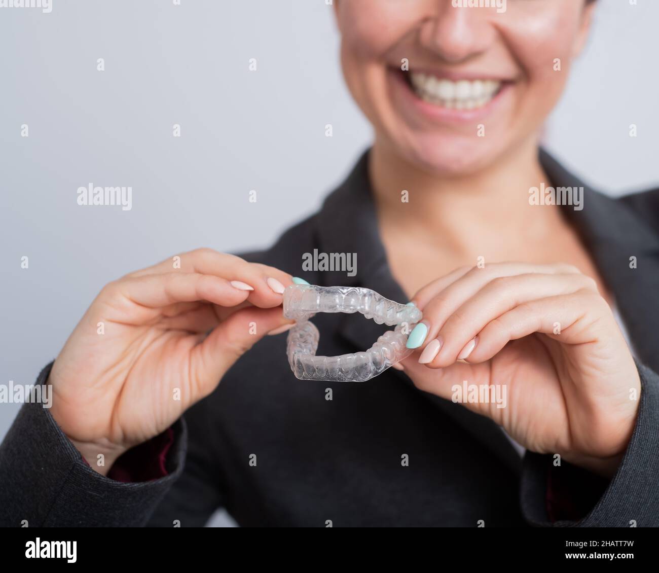 A woman is holding a transparent plastic mouth guard. Orthodontist's
