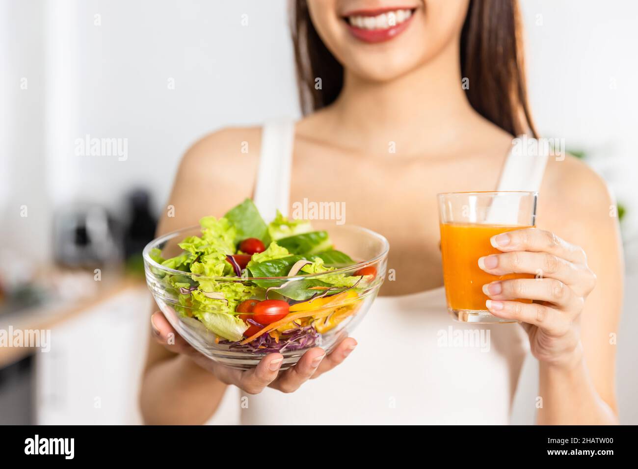 Close up Happy Asian healthy woman smiled and holding glass of orange juice and vegetable salad to diet and eat clean food Stock Photo