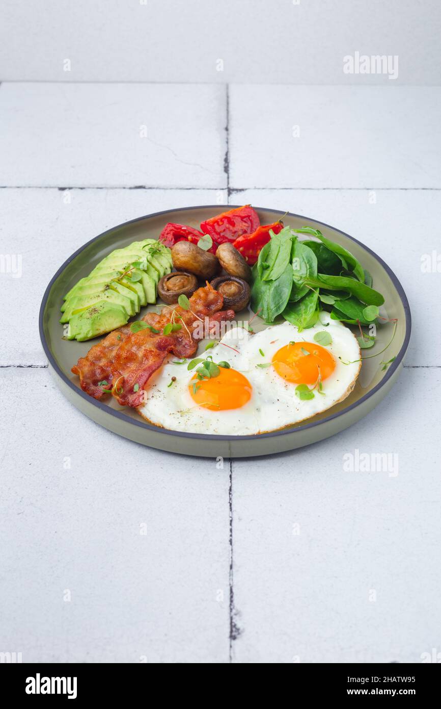 Healthy keto breakfast with egg, avocado, cheese and bacon Stock Photo