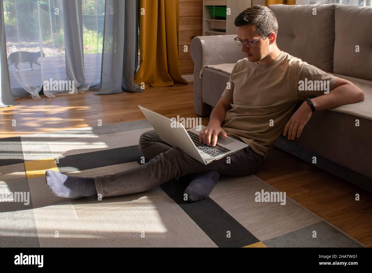 Home office in a sunny loft apartment. Man sitting on the floor and working Stock Photo