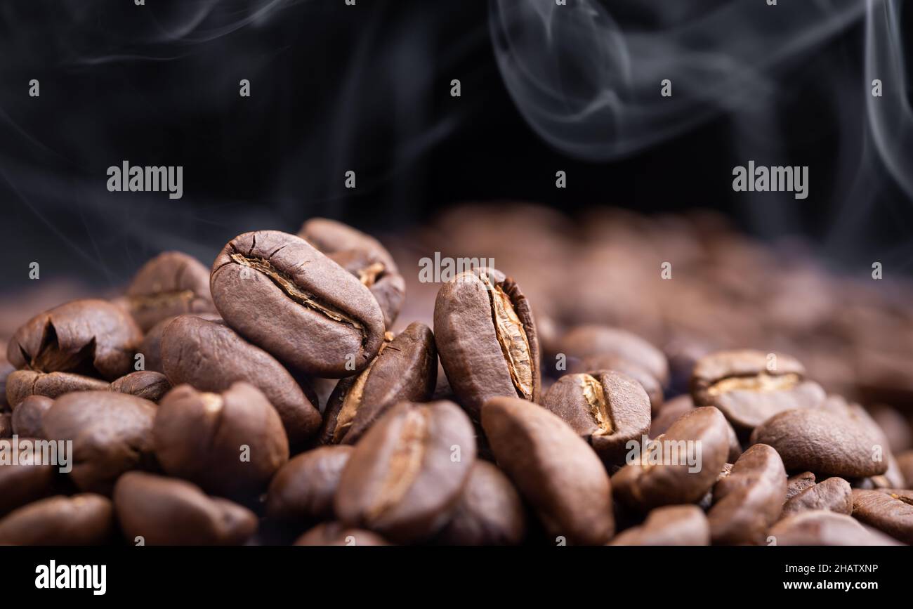 Aroma roasted coffee beans with smoke rising over dark background Stock ...