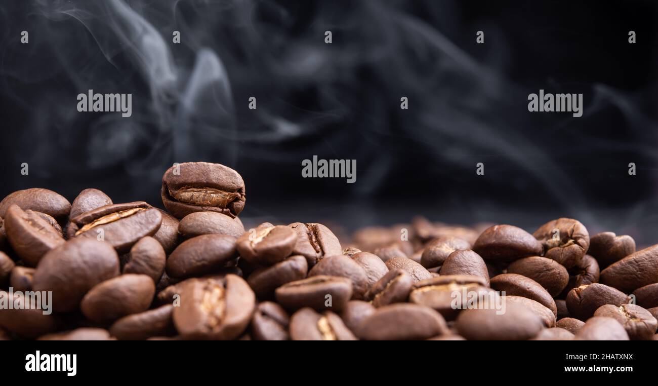 Aroma roasted coffee beans with smoke rising over dark background Stock ...