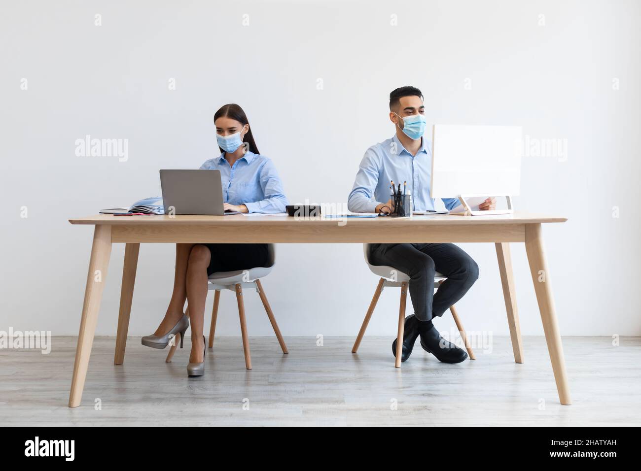 Colleagues in disposable face masks working on pc at office Stock Photo