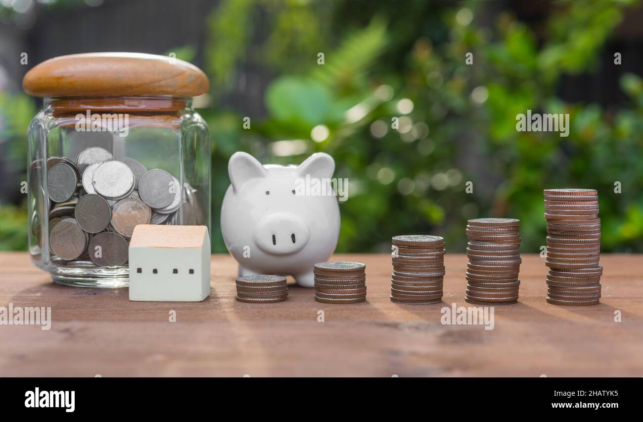 Piggy bank,money coins and house model on wood table with nature ...