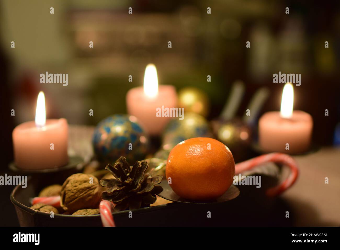 Three burning candles with a manadarin and a pine cone as christmas decoration Stock Photo