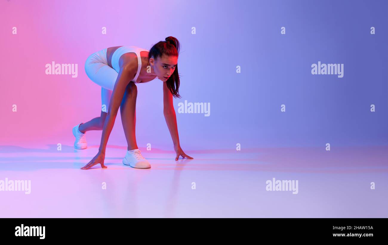 Female Runner Standing In Crouch Start Position Over Neon Background ...