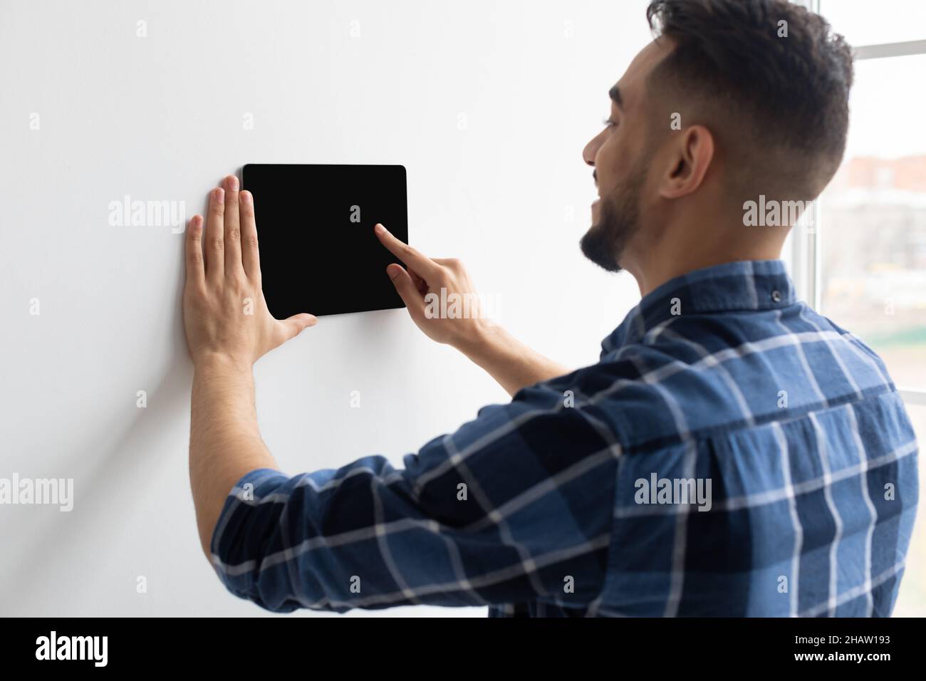 Happy man using smart wall home control system Stock Photo