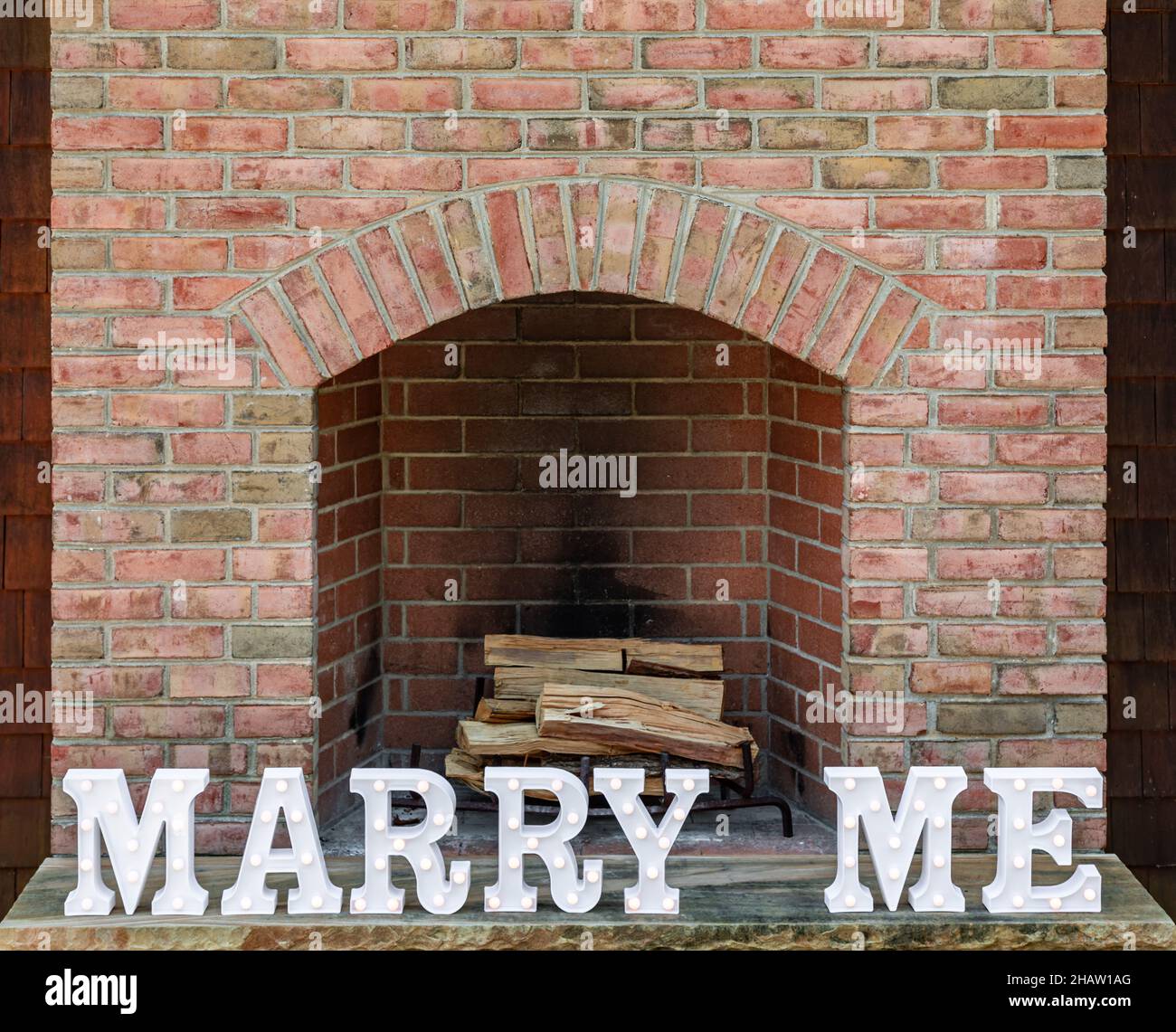 The words Marry Me in front of a brick fireplace Stock Photo