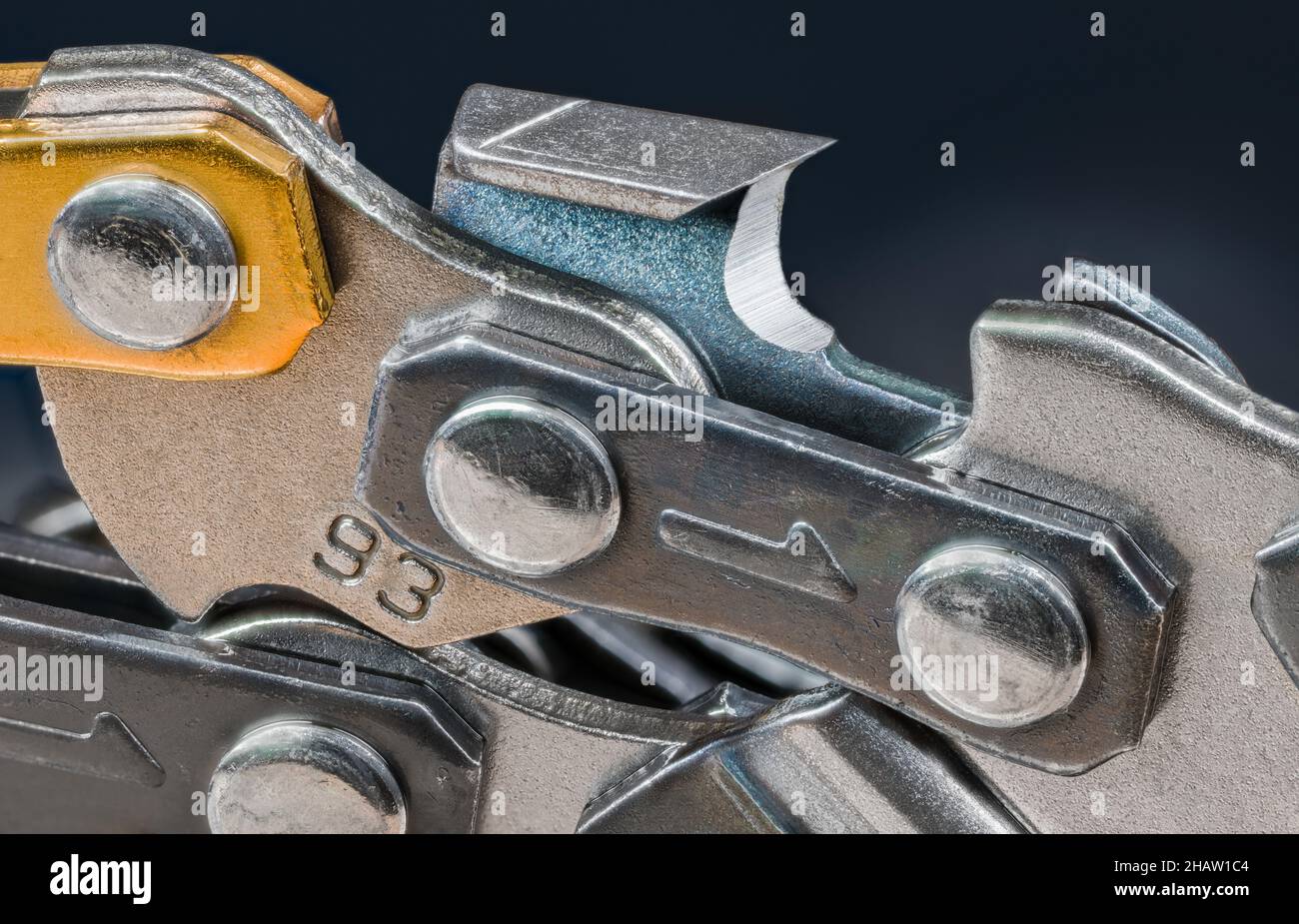 Sharp steel tooth of chainsaw chain detail on a dark blue background