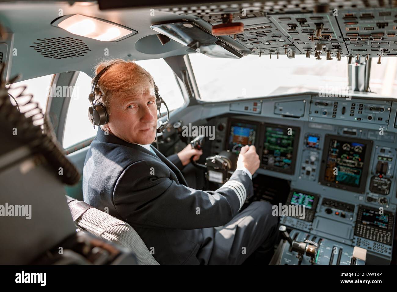 Male pilot in headphones sitting in airplane cockpit Stock Photo Alamy