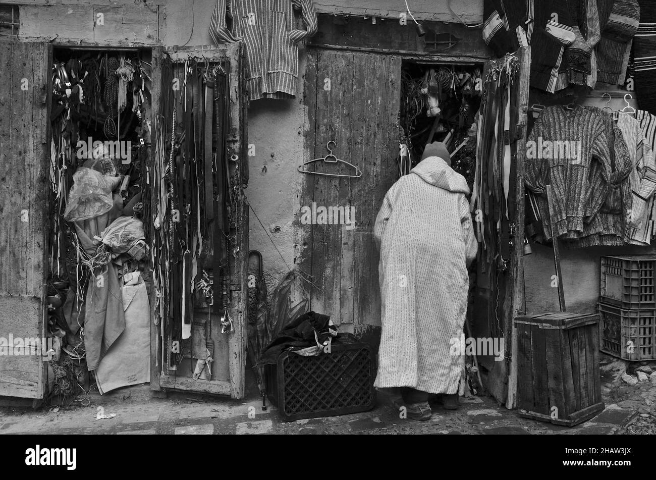 Man in jellaba in front of souvenir shop, salesman in hooded coat in front of shop, Chefchaouen, Marikko Stock Photo