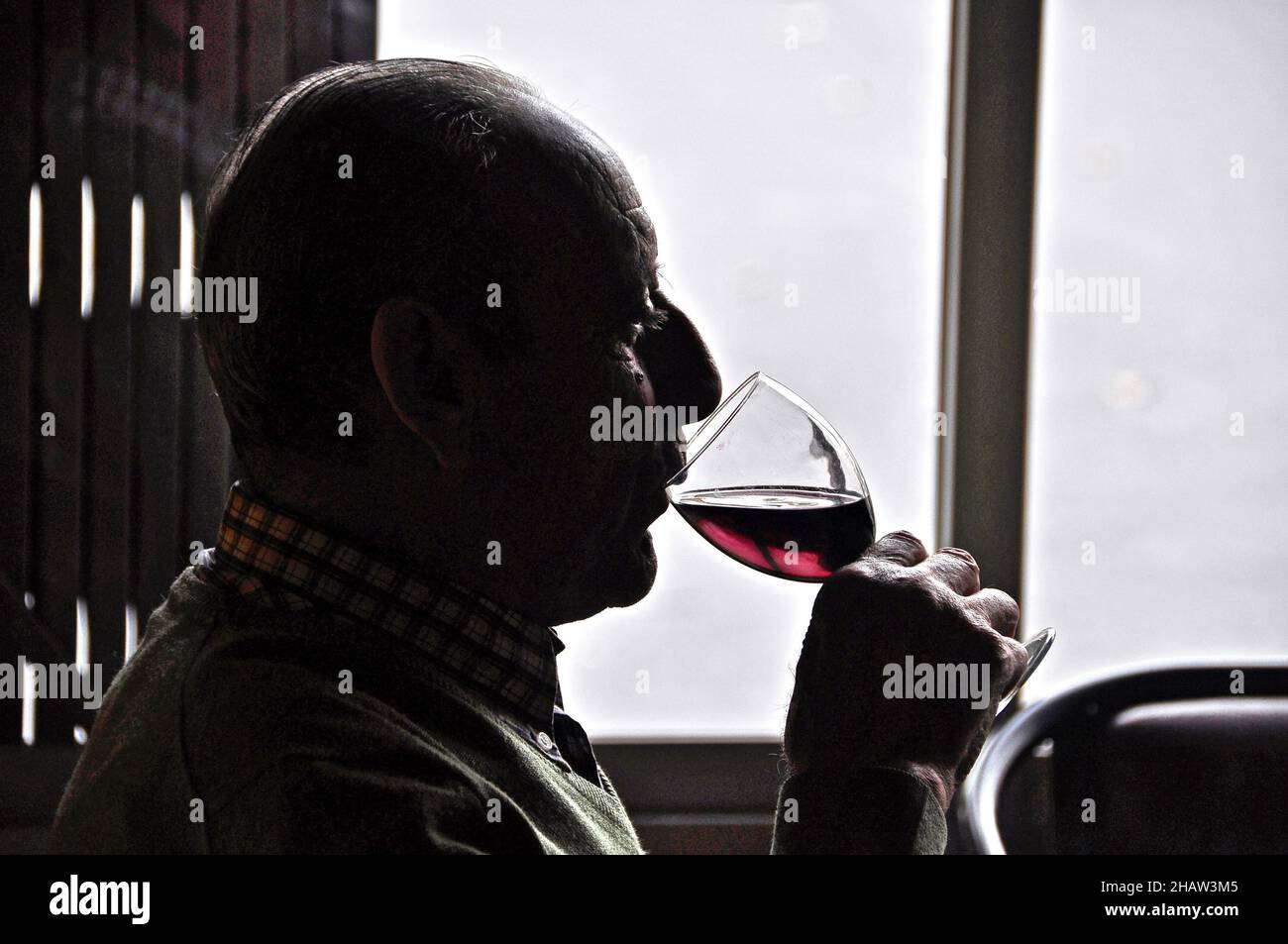 Old man drinking red wine against the light red wine drinker puts on