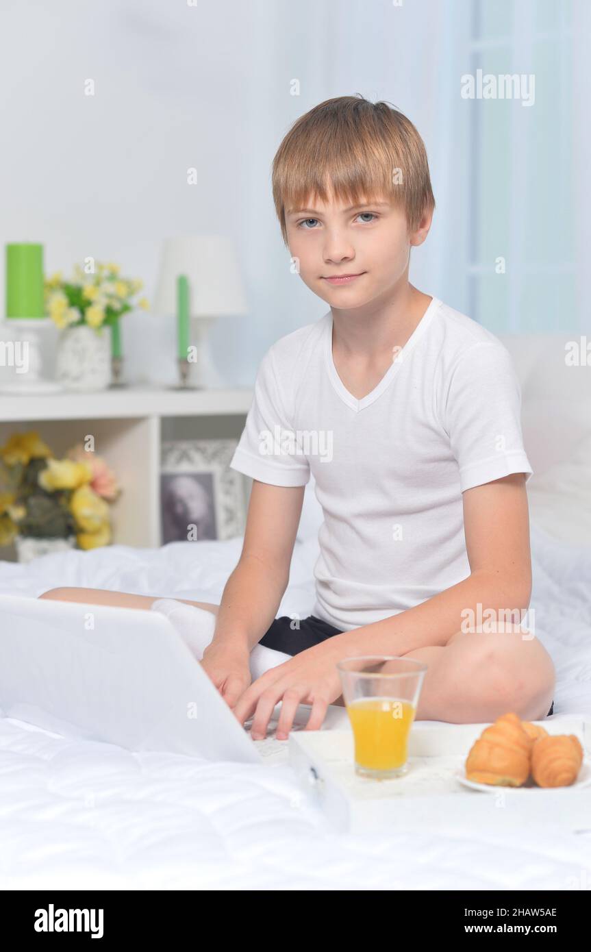 Boy with laptop on bed in the morning Stock Photo - Alamy