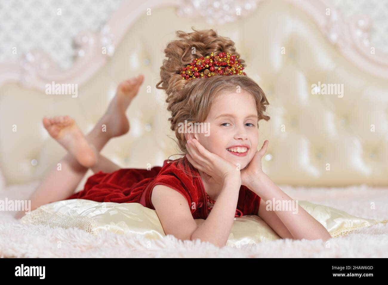 Portrait of cute little girl in red dress lying on bed Stock Photo - Alamy