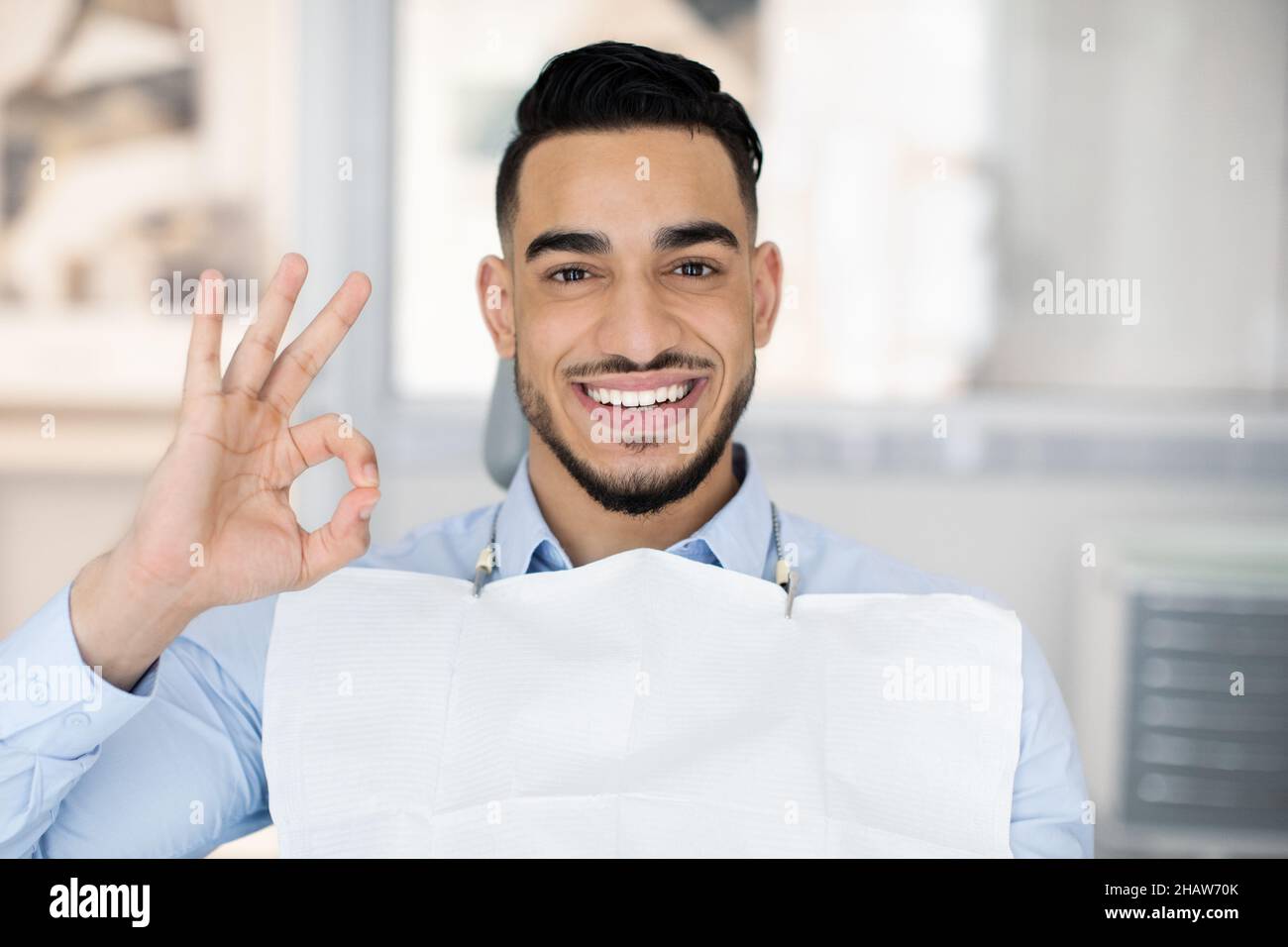 Portrait Of Happy Handsome Arab Man In Dental Chair Showing Ok Gesture Stock Photo