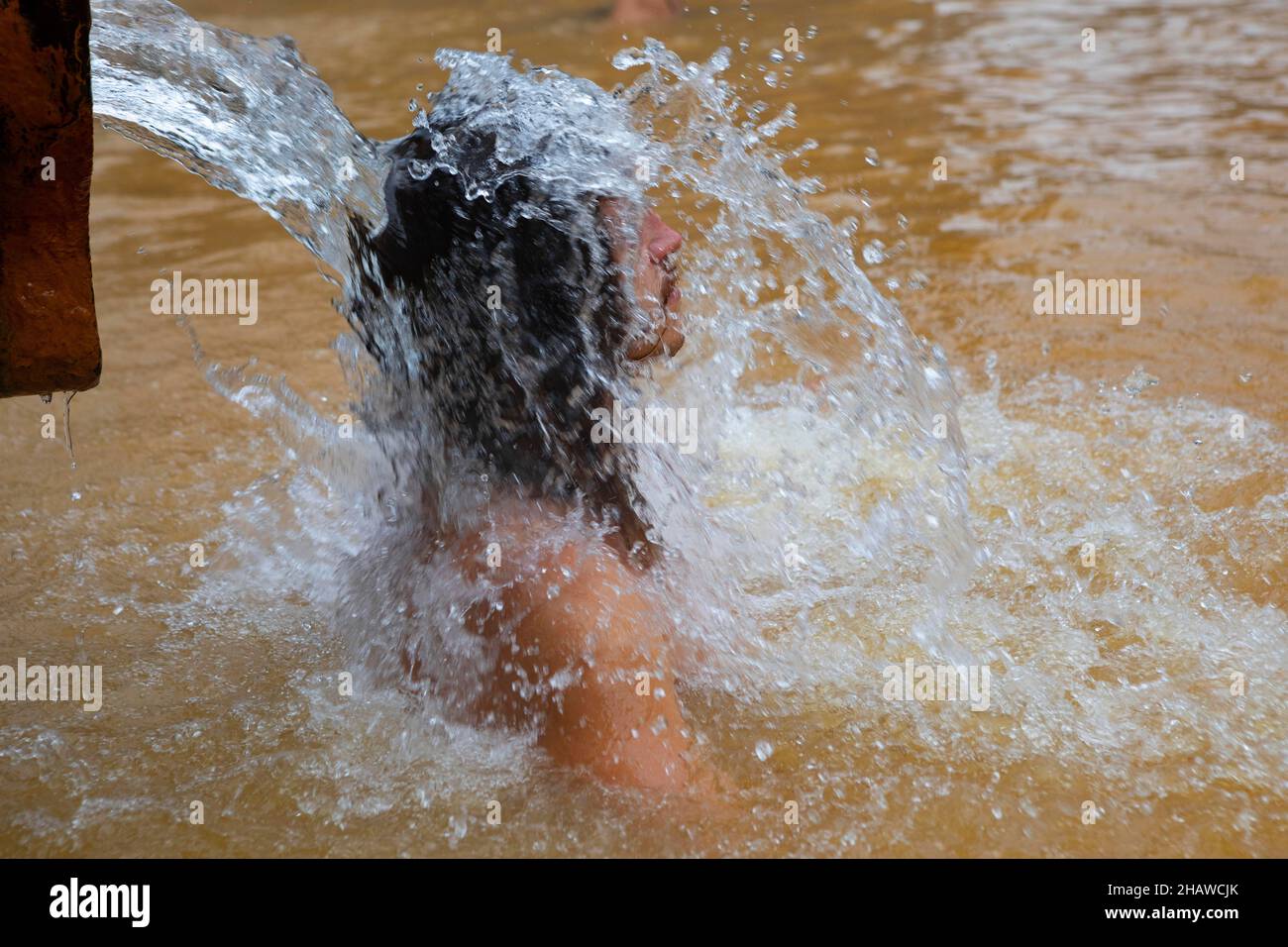 Botanical garden, man under water jet in thermal water pool in Terra Nostra Park, Furnas, Sao Miguel Island, Azores, Portugal Stock Photo