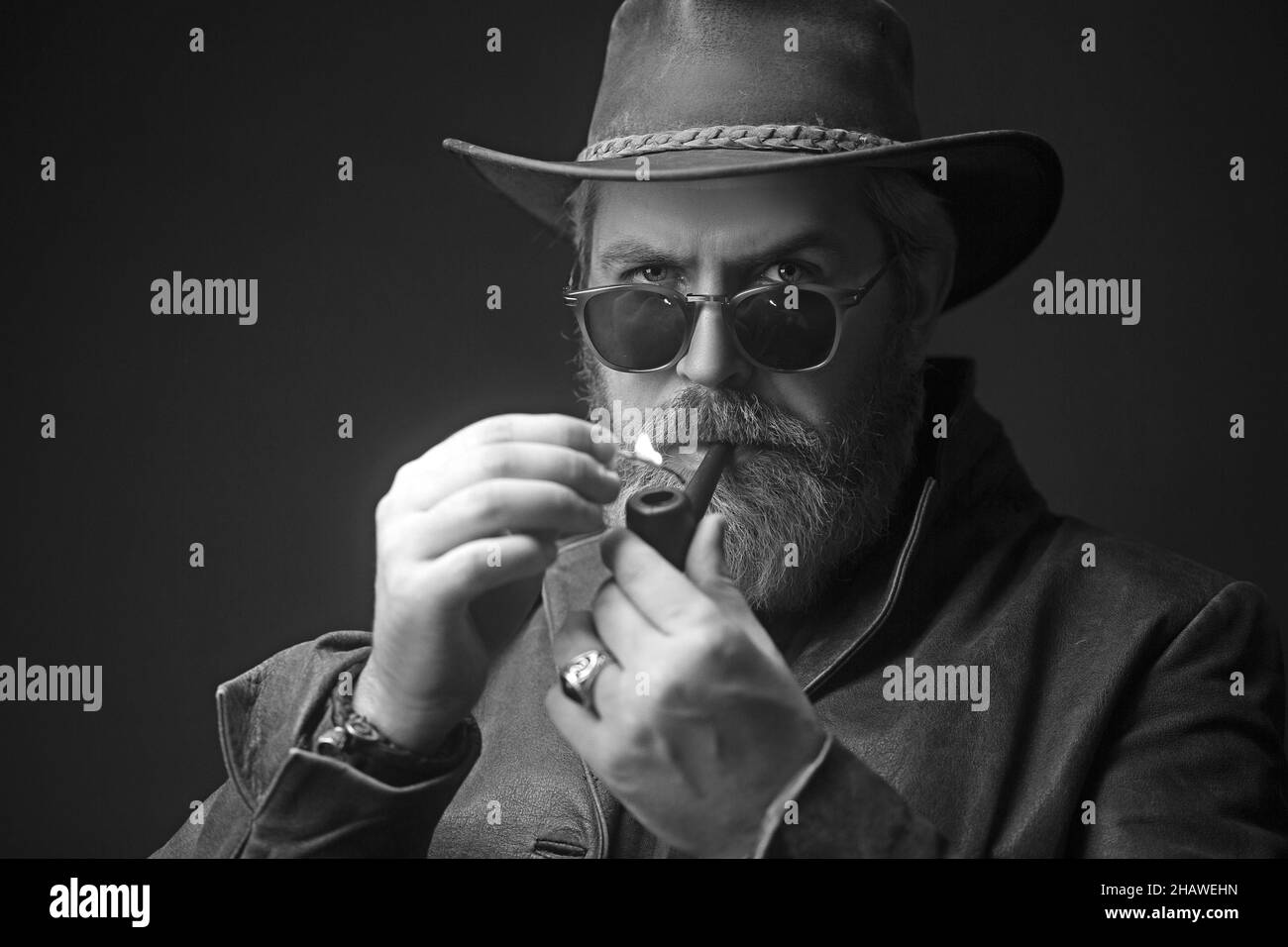 Menacing vintage cowboy standing with pipe for smoking. Stock Photo