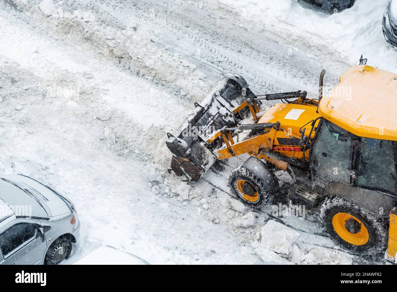 Tractor loader machine uploading dirty snow into dump truck. Cleaning ...