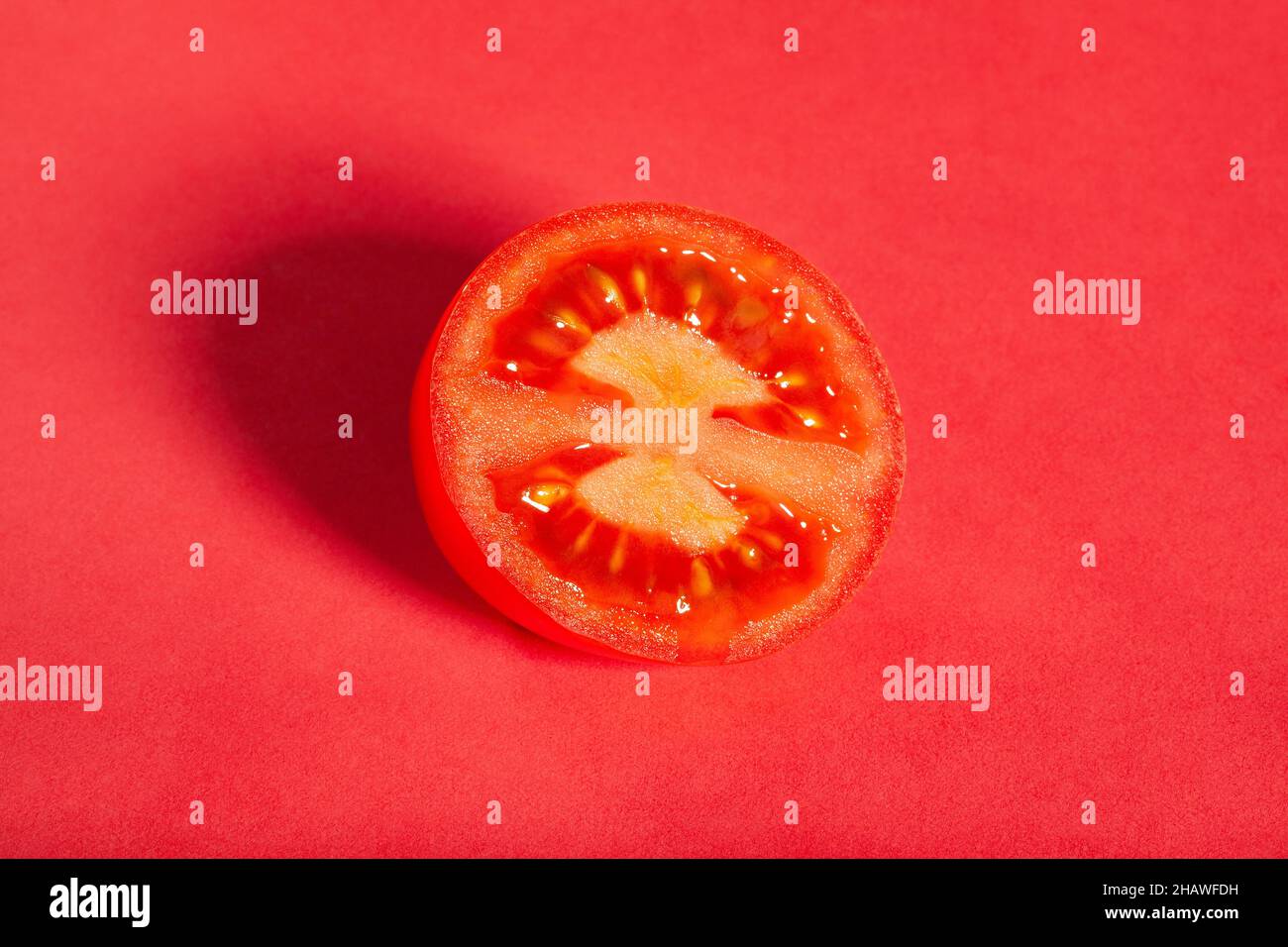 sliced plum tomato on red background Stock Photo