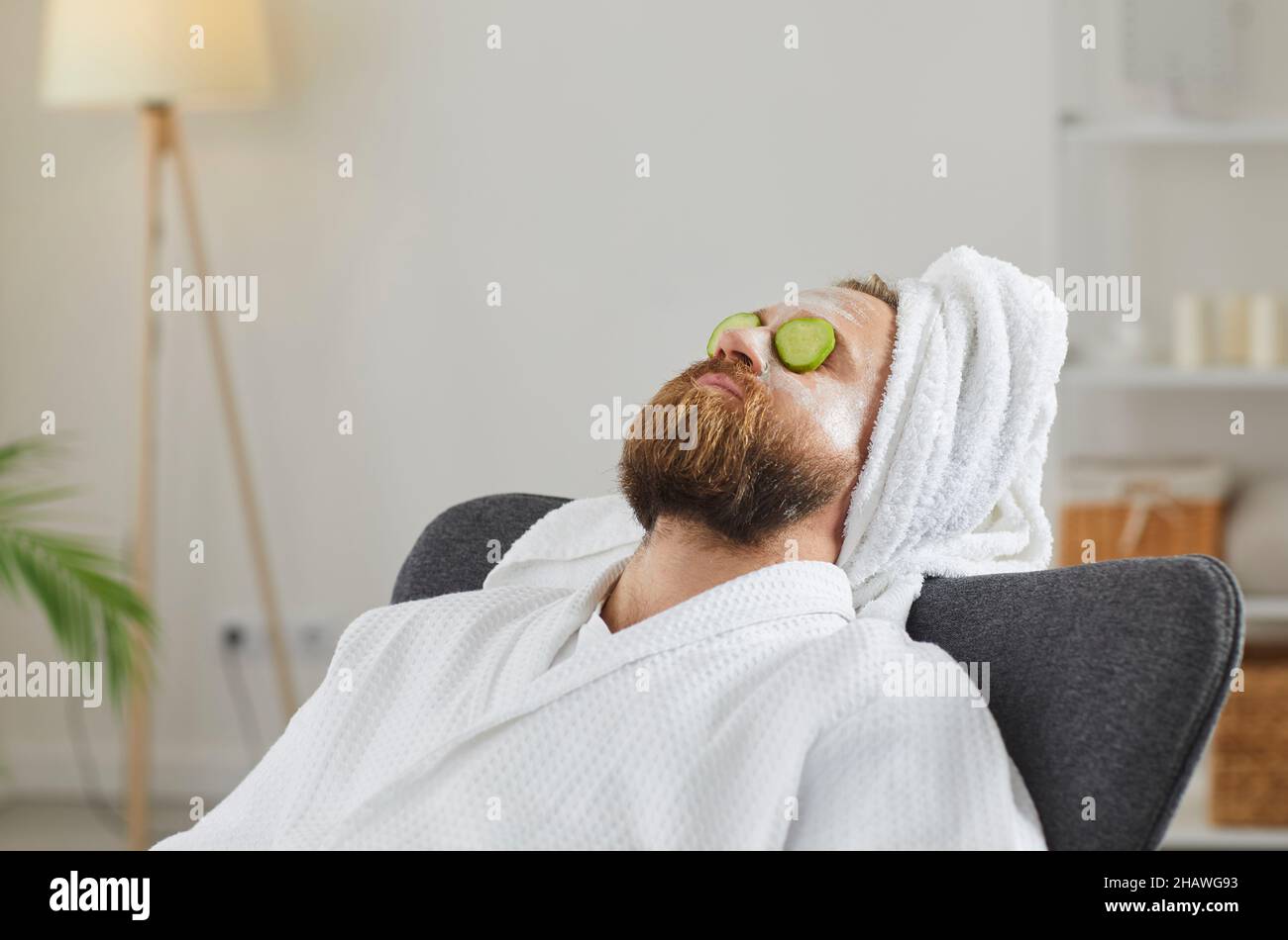 Relaxed man with beauty mask on face and cucumber slices on eyes enjoying spa day at home Stock Photo