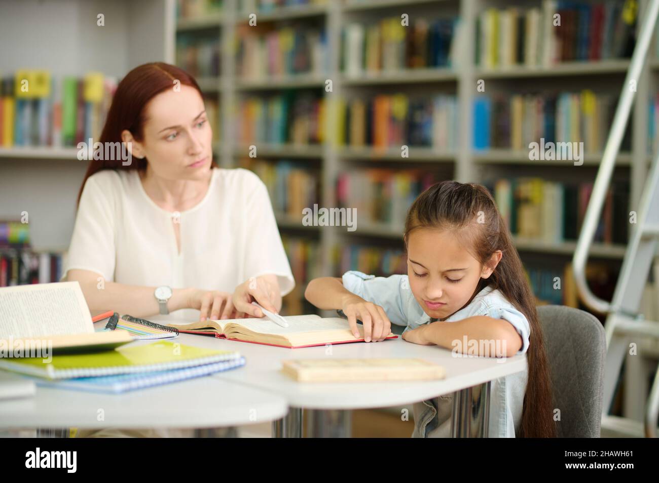 Woman looking at girl refusing to study Stock Photo