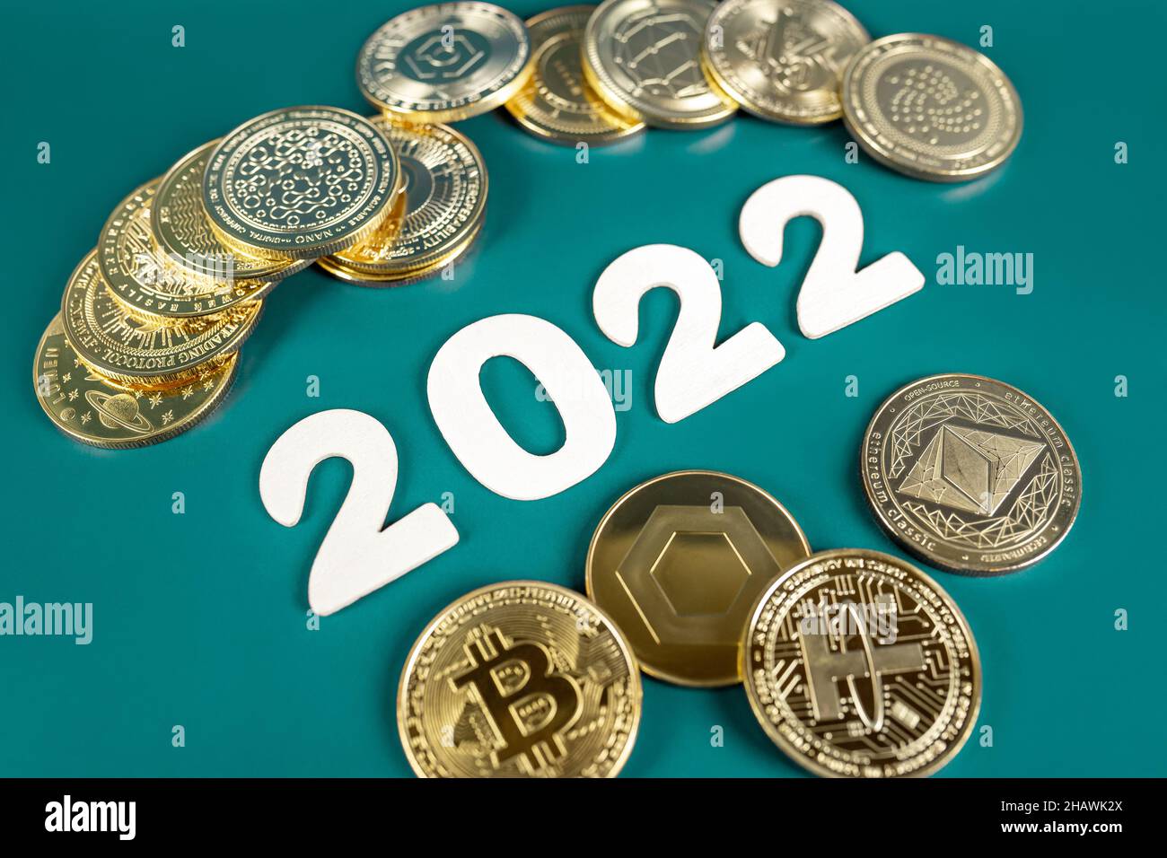Cryptocurrency in 2022 price value prediction, forecast concept. Golden crypto coins Bitcoin, Ethereum, Tether, Nano, Chainlink and other next to the year numbers on green background. Stock Photo