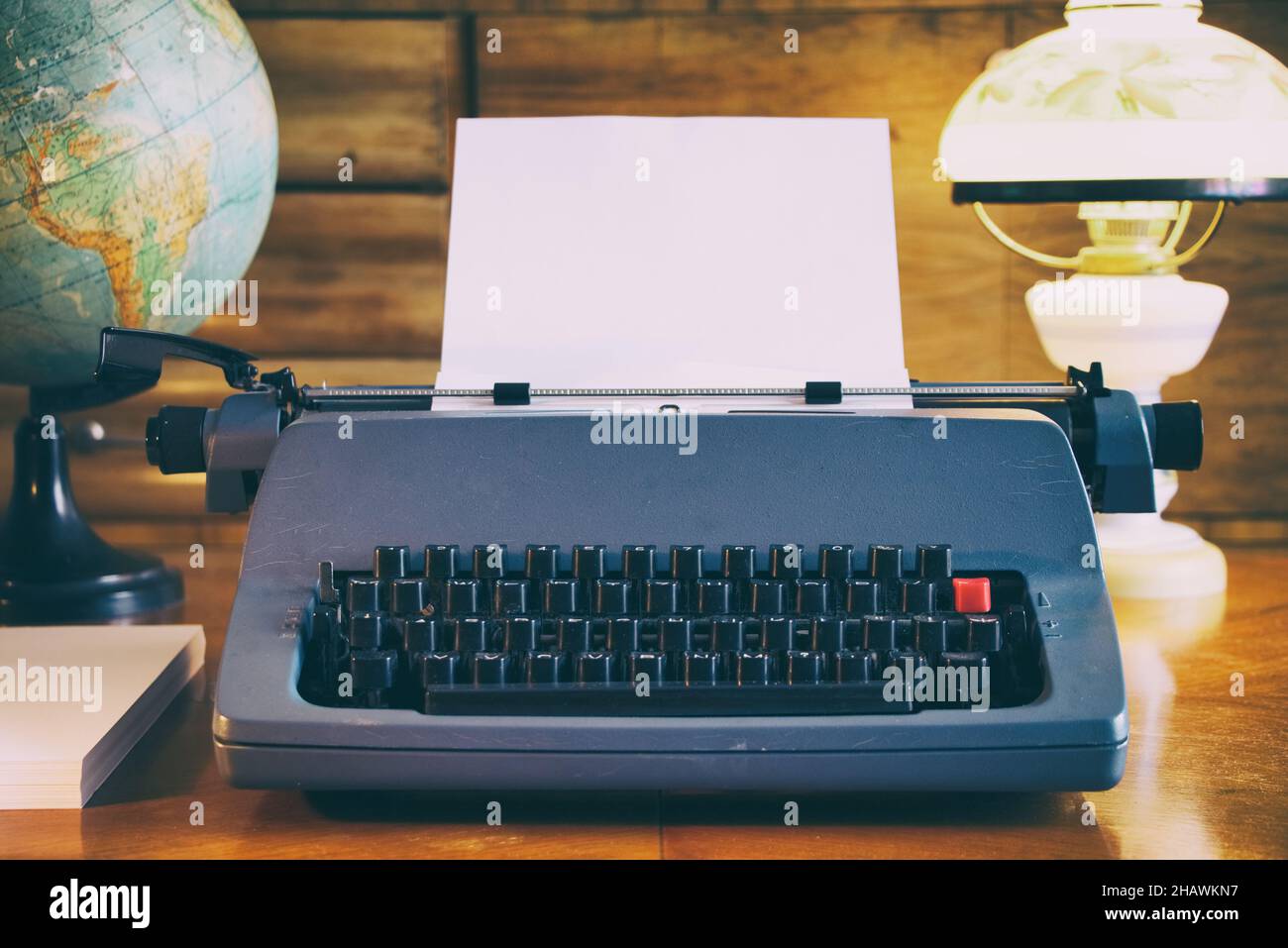Still life of old typewriter with empty sheet, globe and old fashioned lamp, retro journalism concept Stock Photo