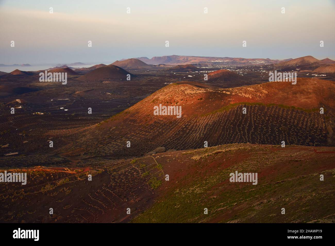 The wine-growing area of La Geria, Lanzarote at sunrise. In the background the volcanos of the Timanfaya National Park. Canary Islands, Spain. Stock Photo