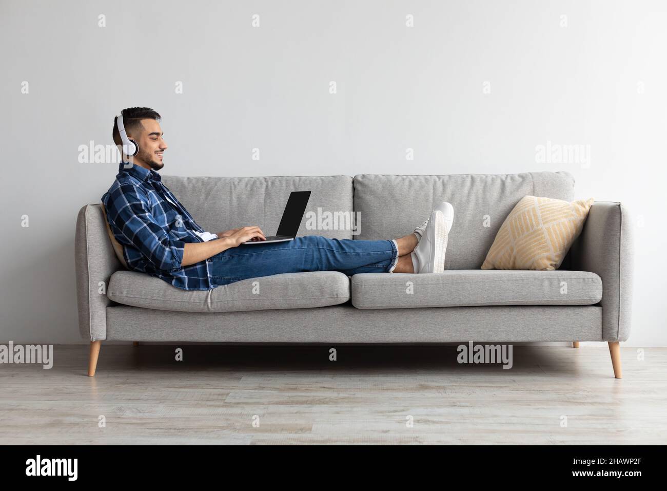 Smiling Arab man in headphones using pc at home Stock Photo