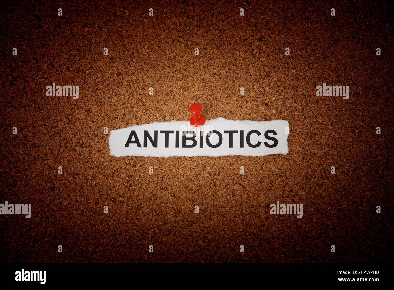 A crumpled piece of paper with the word Antibiotics on it pinned to a corkboard. Close up. Stock Photo