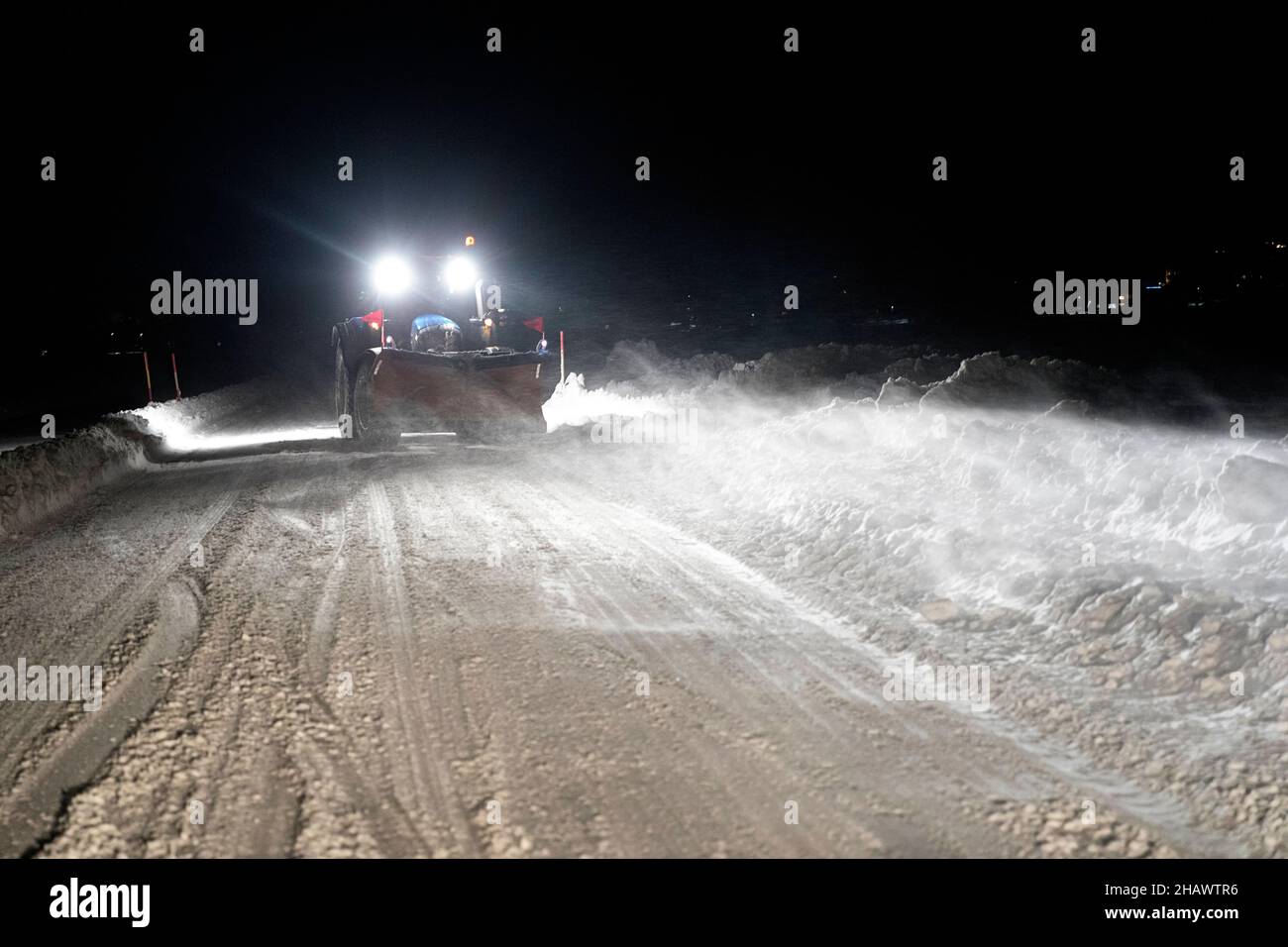 Snow removal vehicle equipped with snowplow on a winter evening in