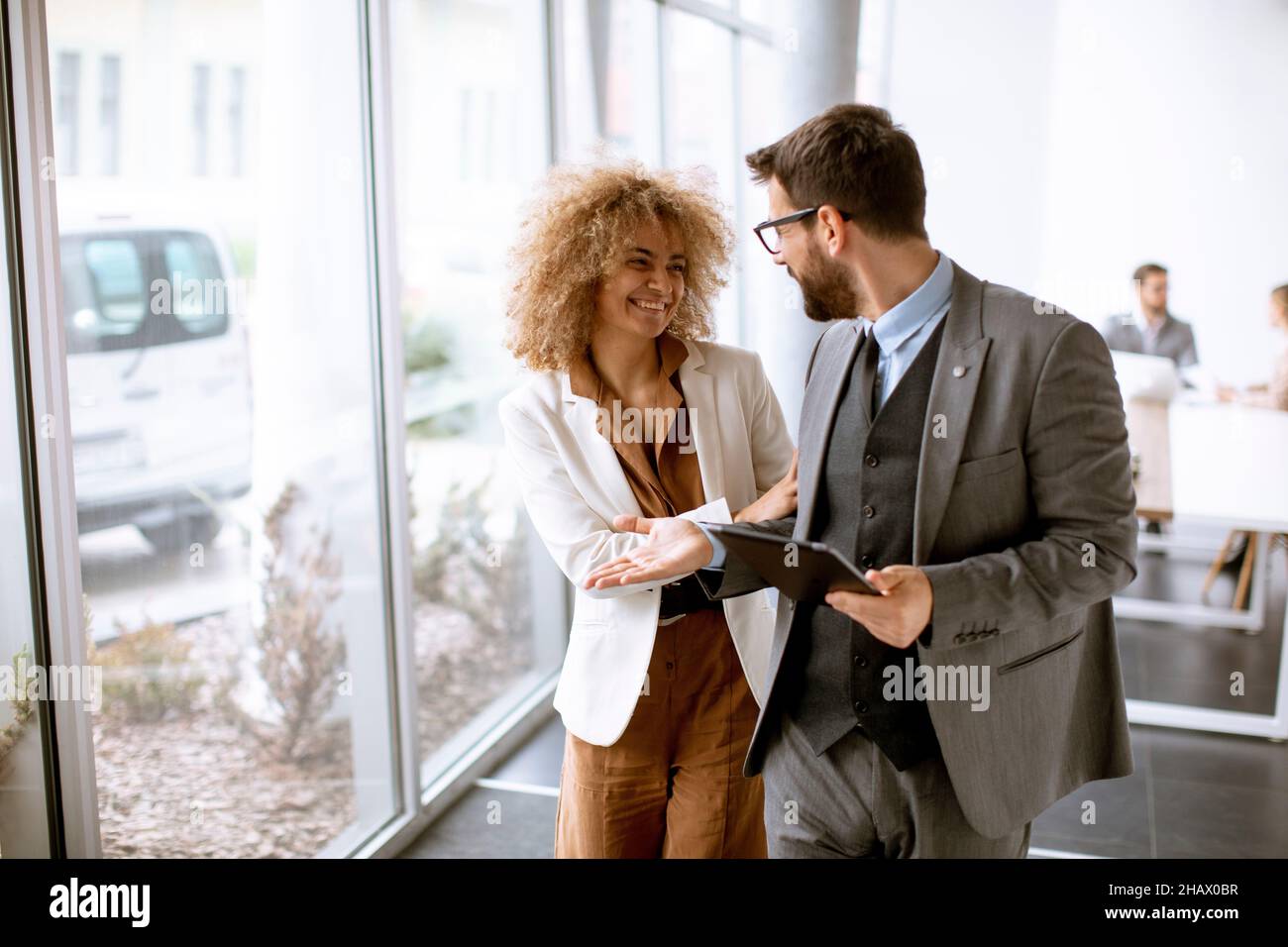 Young multiethnic entrepreneurs standing together and talking in the modern office Stock Photo