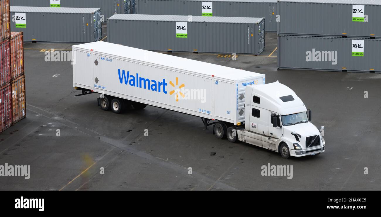 Everett, WA, USA - December 14, 2021; Truck pulling a white 53 foot Walmart shipping container negotiates a path through staks of containers Stock Photo