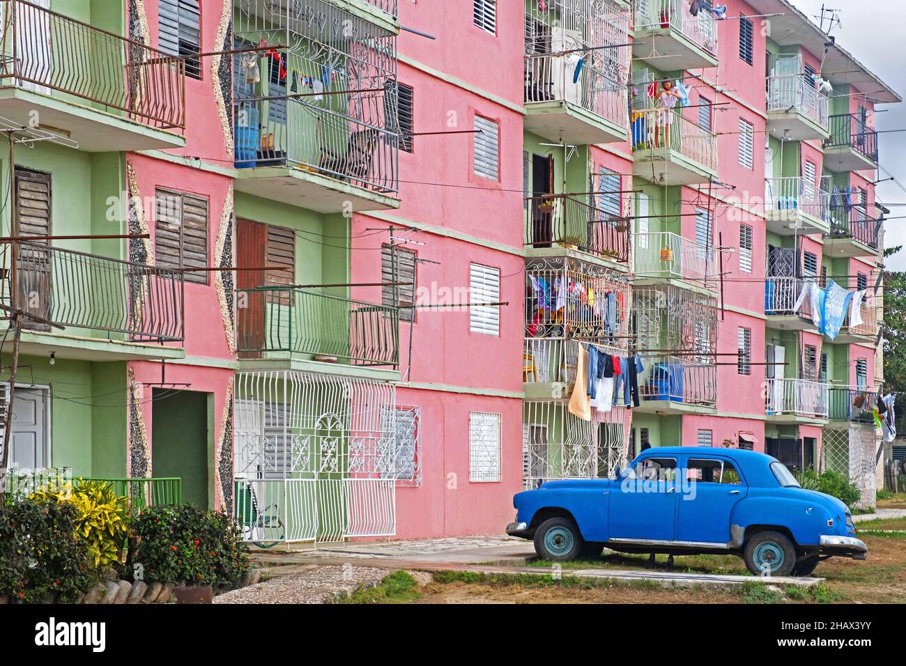 Soviet style apartments / flats in pastel colours and classic 1950s American Plymouth car in the city Florida, Camagüey on the island Cuba, Caribbean Stock Photo
