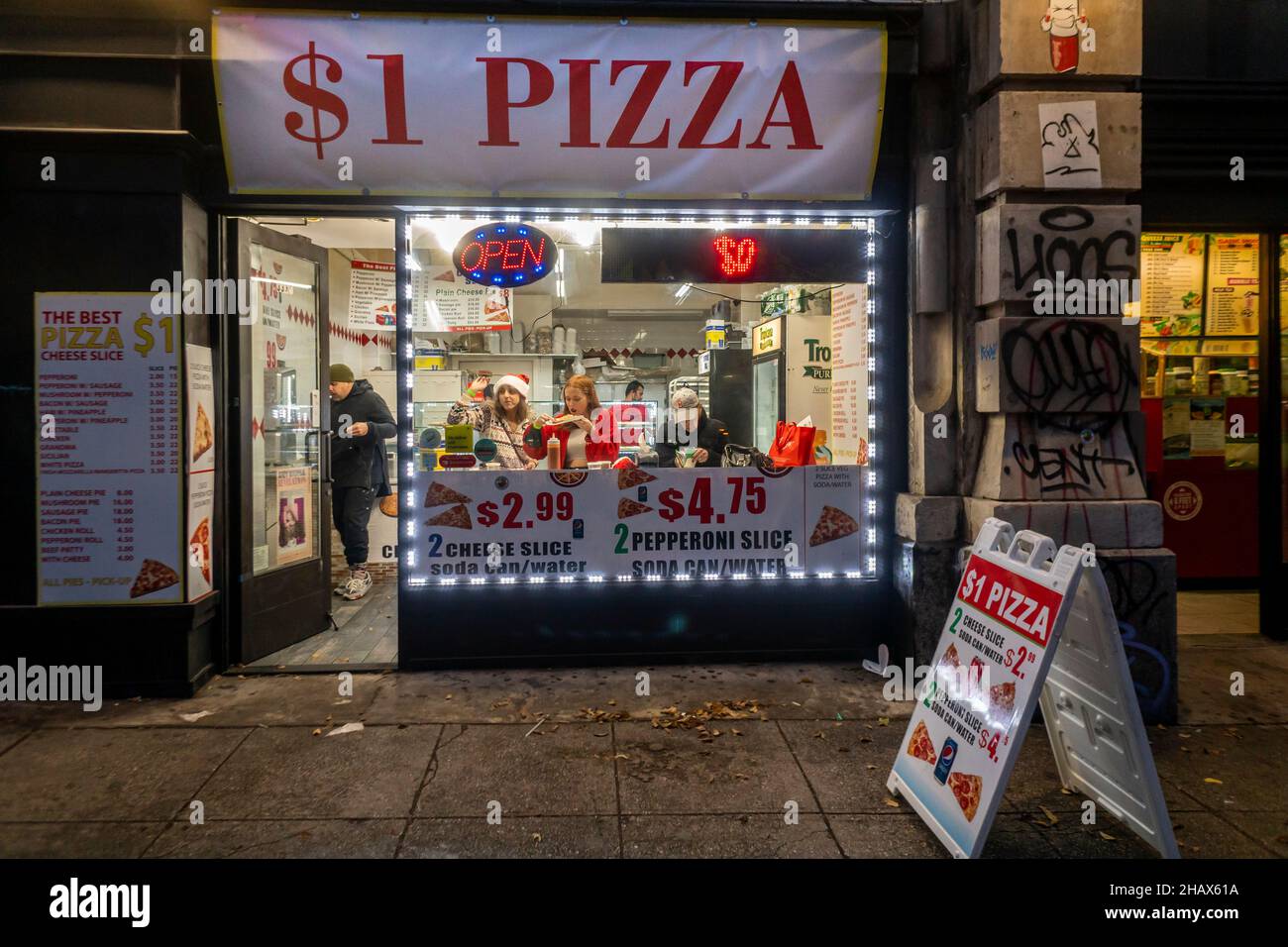 Hungry Santacon participants in a dollar pizzeria in New York on Saturday, December 11, 2021.  SantaCon, primarily a bar crawl in Santa and other Christmas related costumes, attracts thousands of masqueraders going from bar to bar.  (© Richard B. Levine) Stock Photo