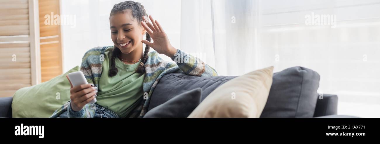 happy african american teenage girl waving hand during video call on ...
