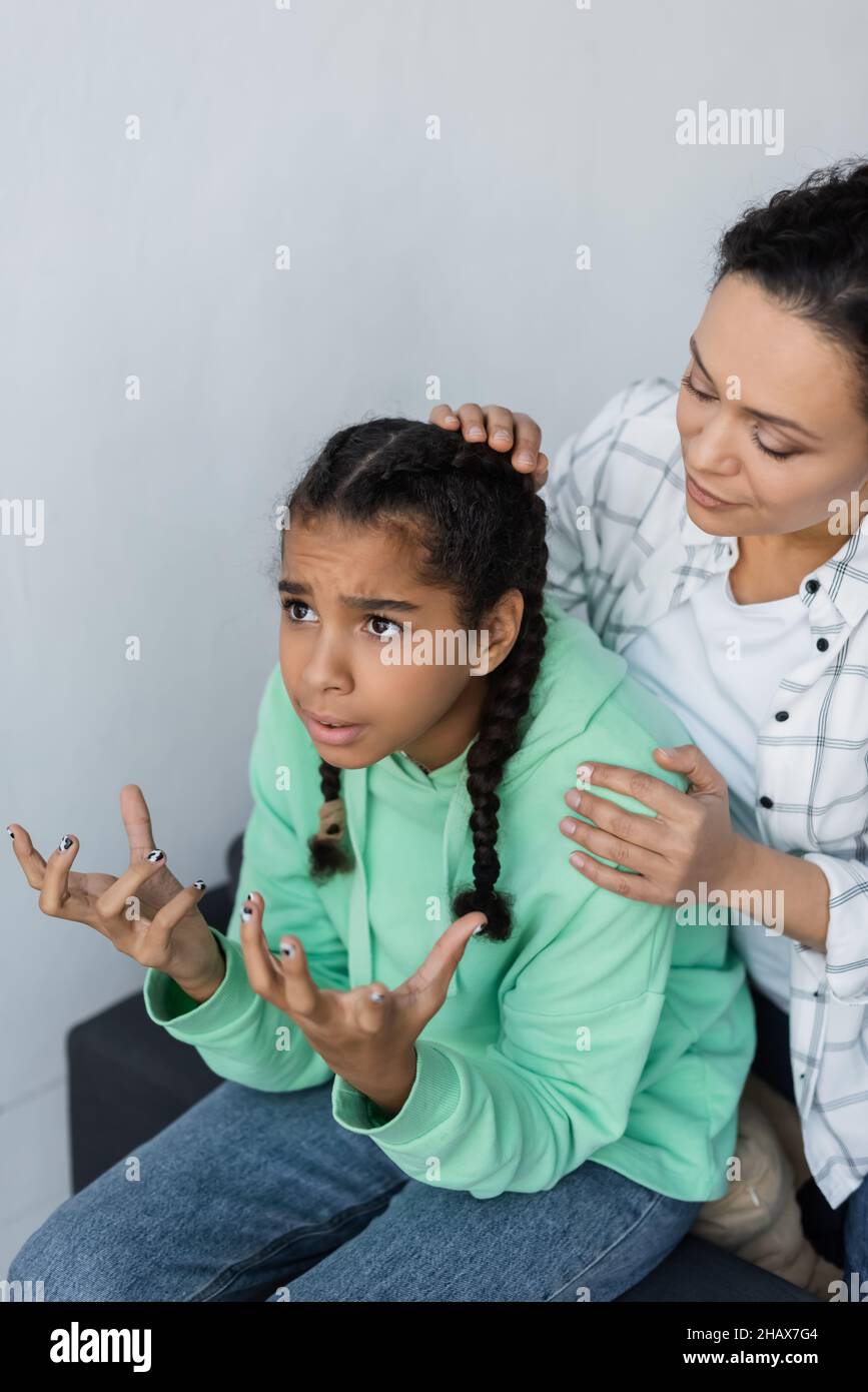 african american woman calming discouraged and gesturing daughter at home Stock Photo