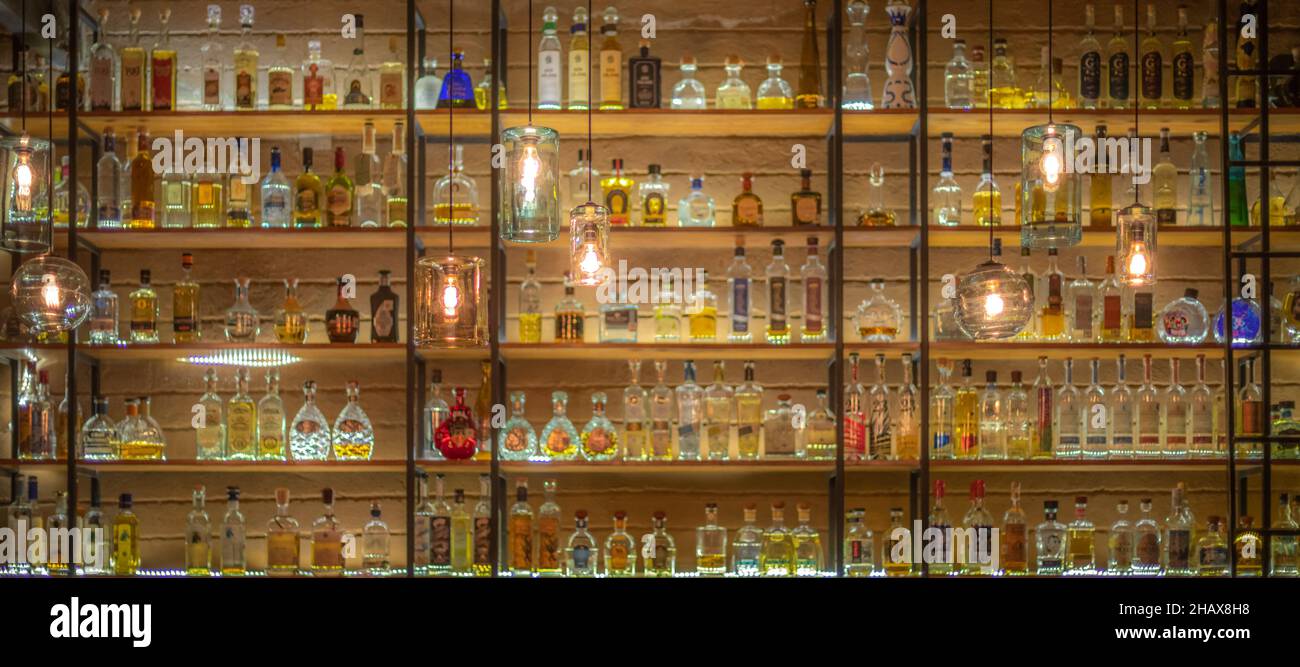 Defocused background of bar counter with various bottles of alcohol ...