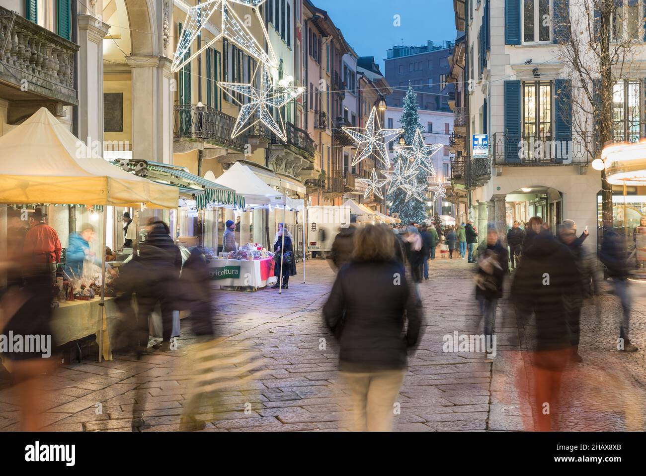 Christmas market at dusk, crowd of people on the street of a city with christmas lights. Historic center of Varese, Corso Matteotti Stock Photo
