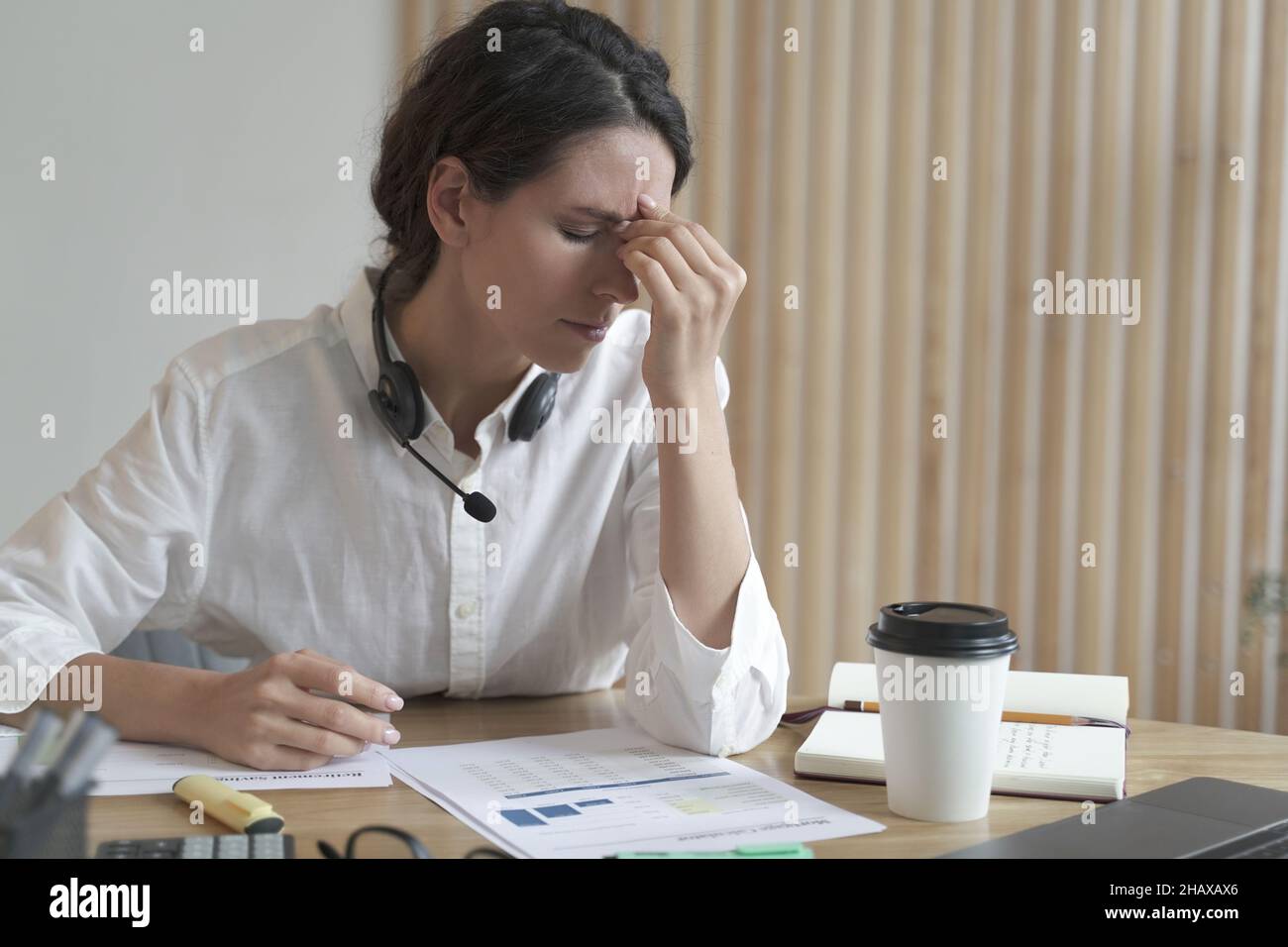 Tired spanish female home office worker massaging nose or inner corners ...