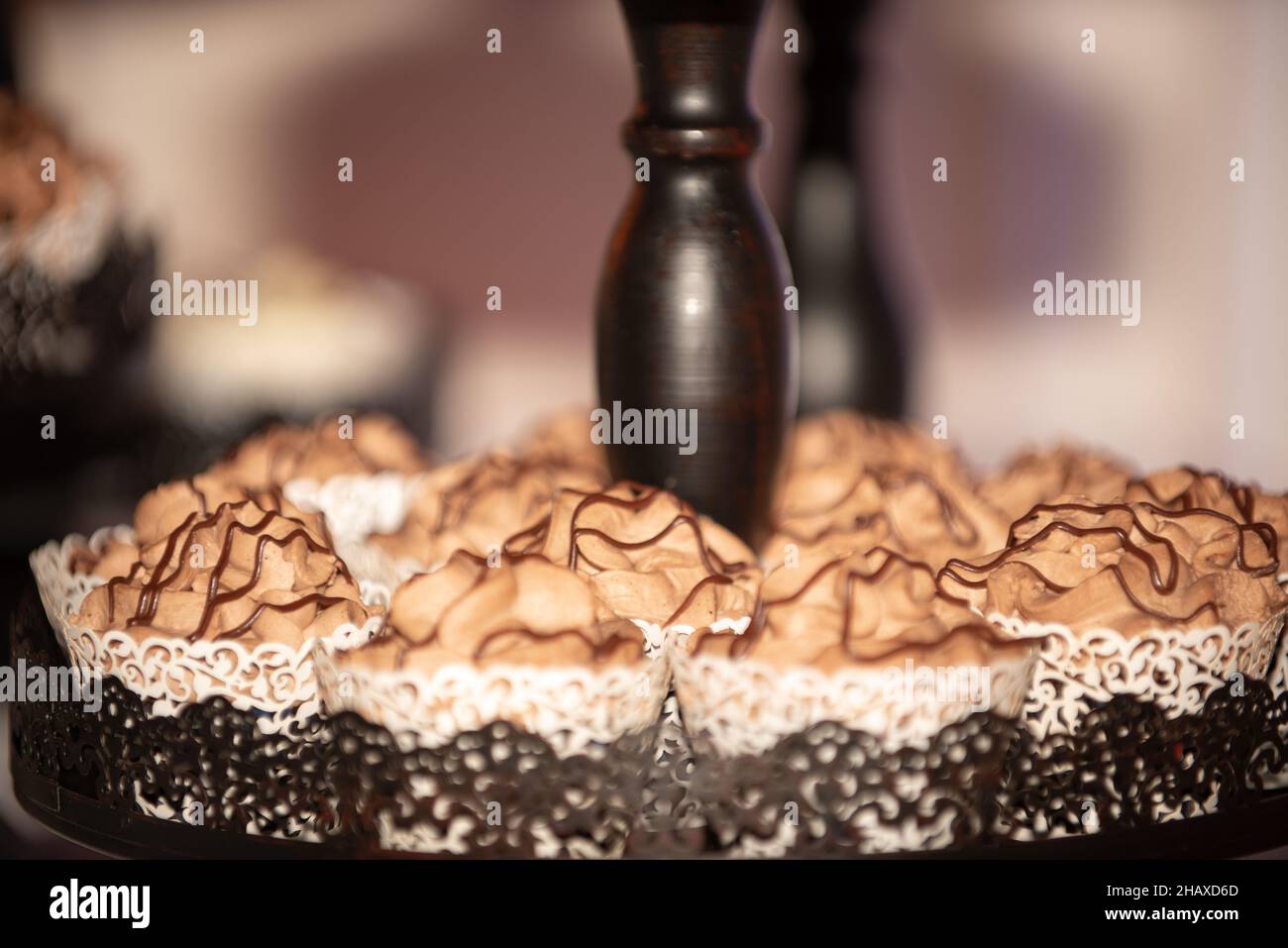 Black ast iron ornate cupcake tower with chocolate cupcakes that have chocolate fuge drizzle Stock Photo