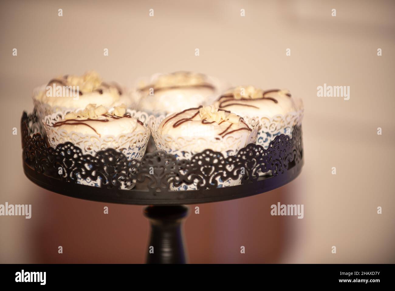 Black ast iron ornate cupcake tower with vanilla cupcakes that have chocolate fuge drizzle Stock Photo
