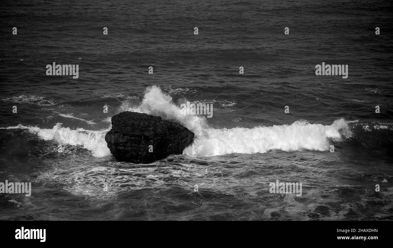 Black and white ocean wave crashes on rocks shoreline powerful natural ...