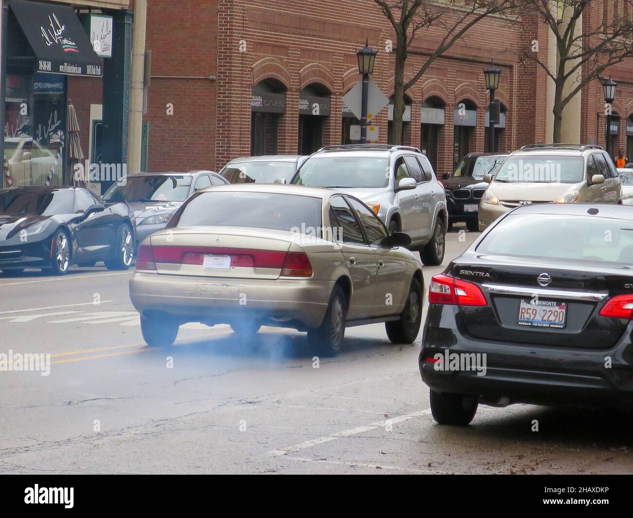 Old Saturn sedan burning oil, spewing bluish smoke. Air pollution. Stock Photo