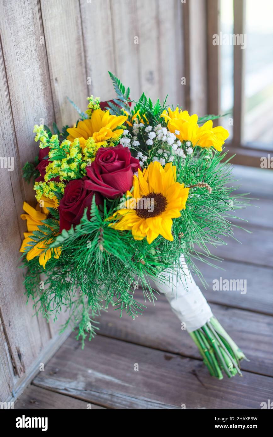 Beatifull sunflower and red roses bridal bouquets on wood porch Stock