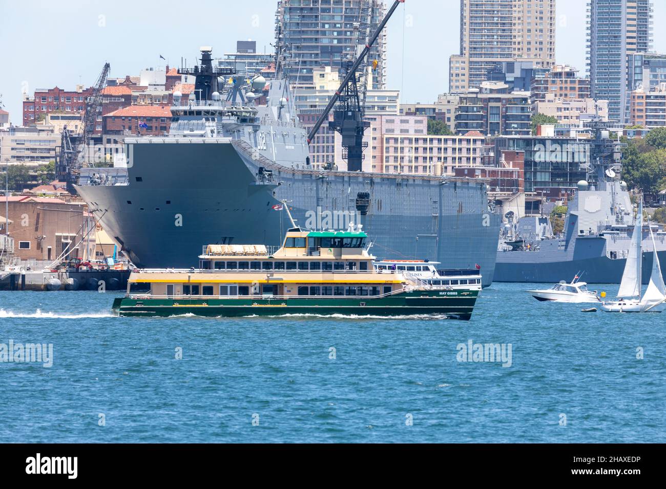 Sydney ferry the May Gibbs passes garden island and HMAS Canberra in Sydney Harbour,NSW,Australia Stock Photo