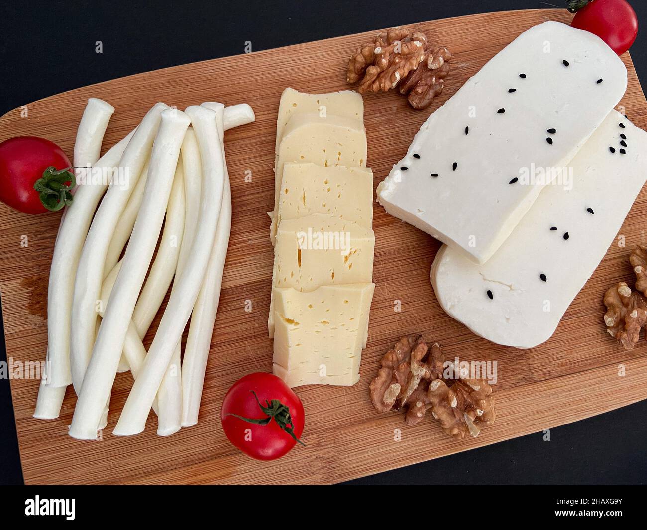 Cheese plate, different cheese types with tomatoes and walnuts. Presentation concept and idea. Stock Photo