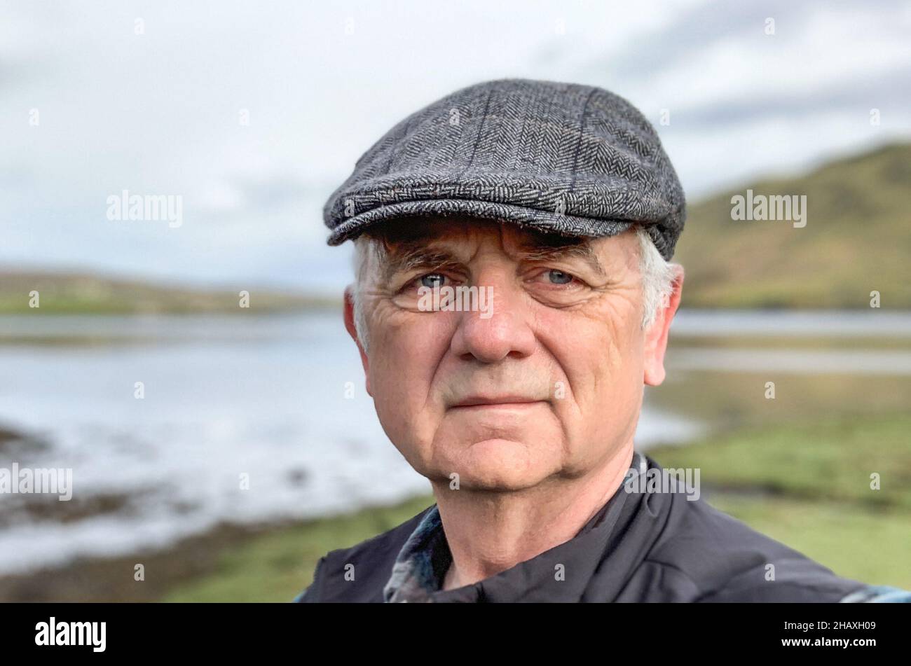 Portrait of a man wearing a flat cap standing in rural landscape, Isle of Skye, Scotland, UK Stock Photo