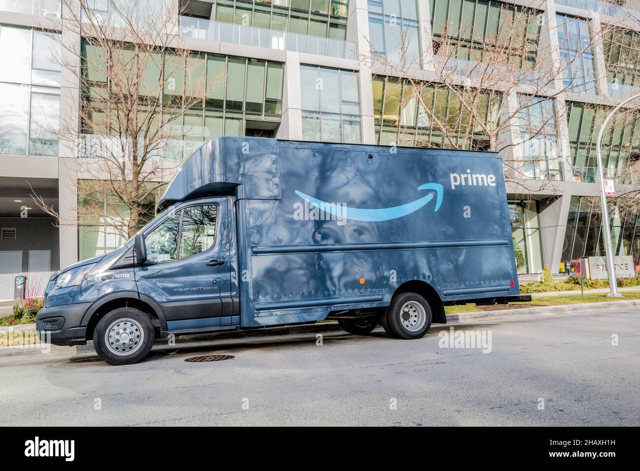 Blue Amazon box truck parked on a Chicago street making deliveries in front of an apartment building. Stock Photo