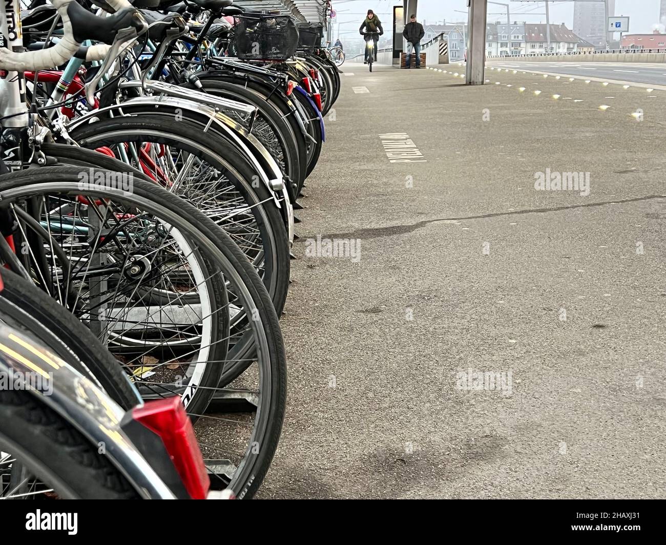 Bicycles parked at bus stop by the train station Hardbrücke in Zurich. On background there is a person riding a bicycle approaching. Stock Photo